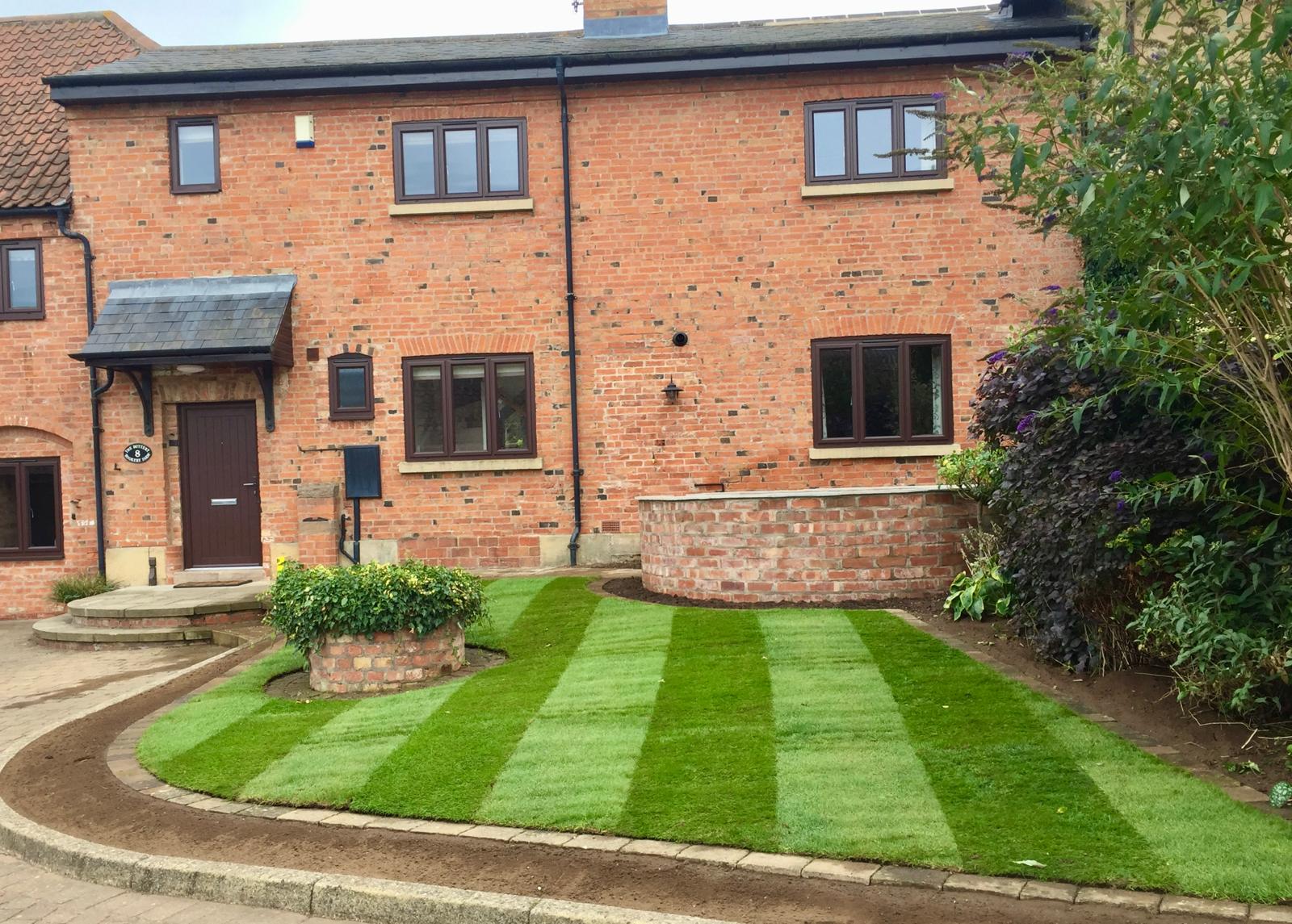 Front garden curved brick wall with new striped lawn