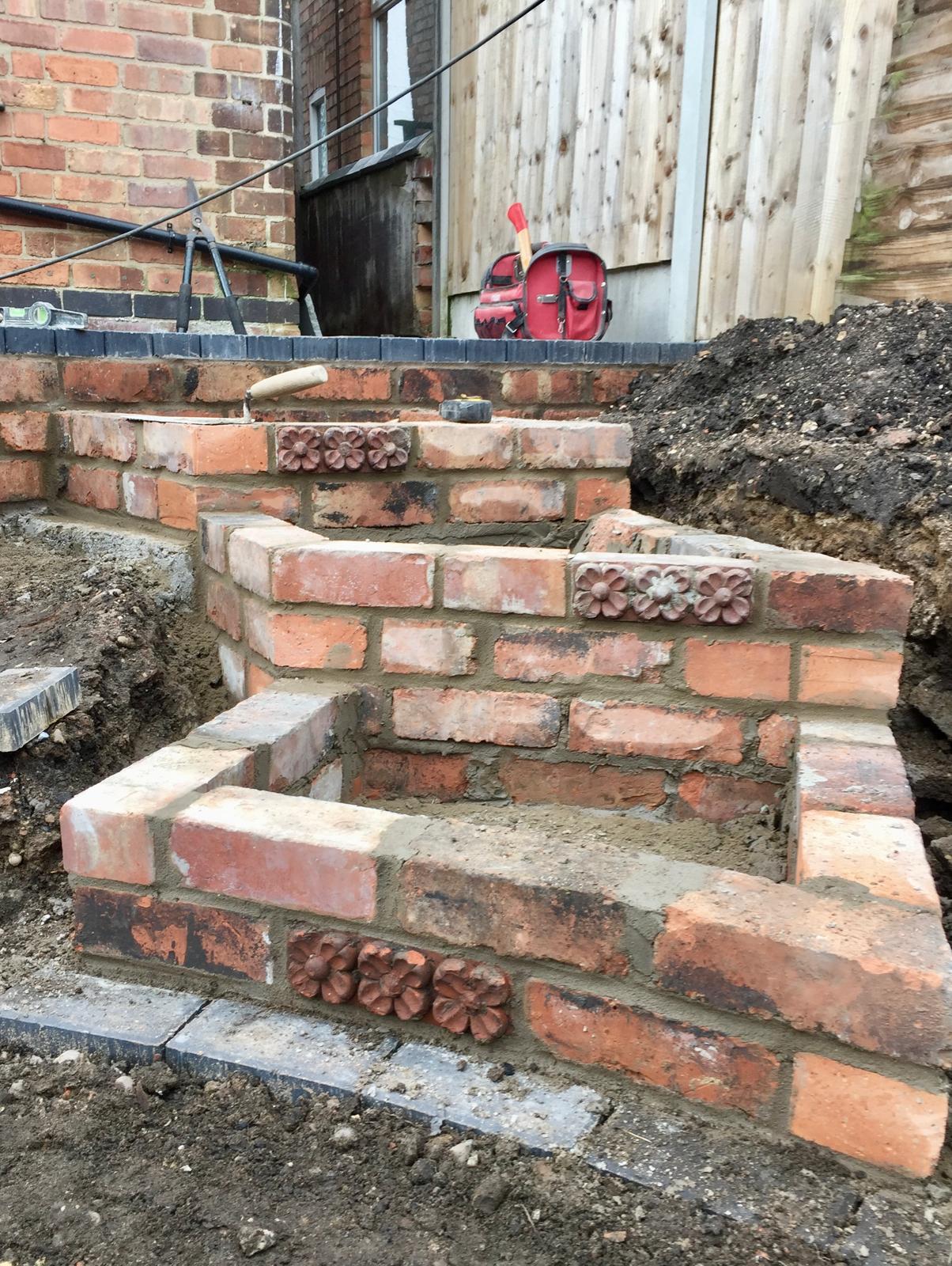 Decorative brick steps with flower pattern inserts under construction