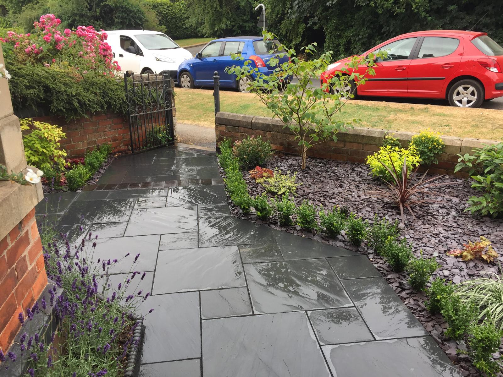 Black slate garden path to gate with mixed planting