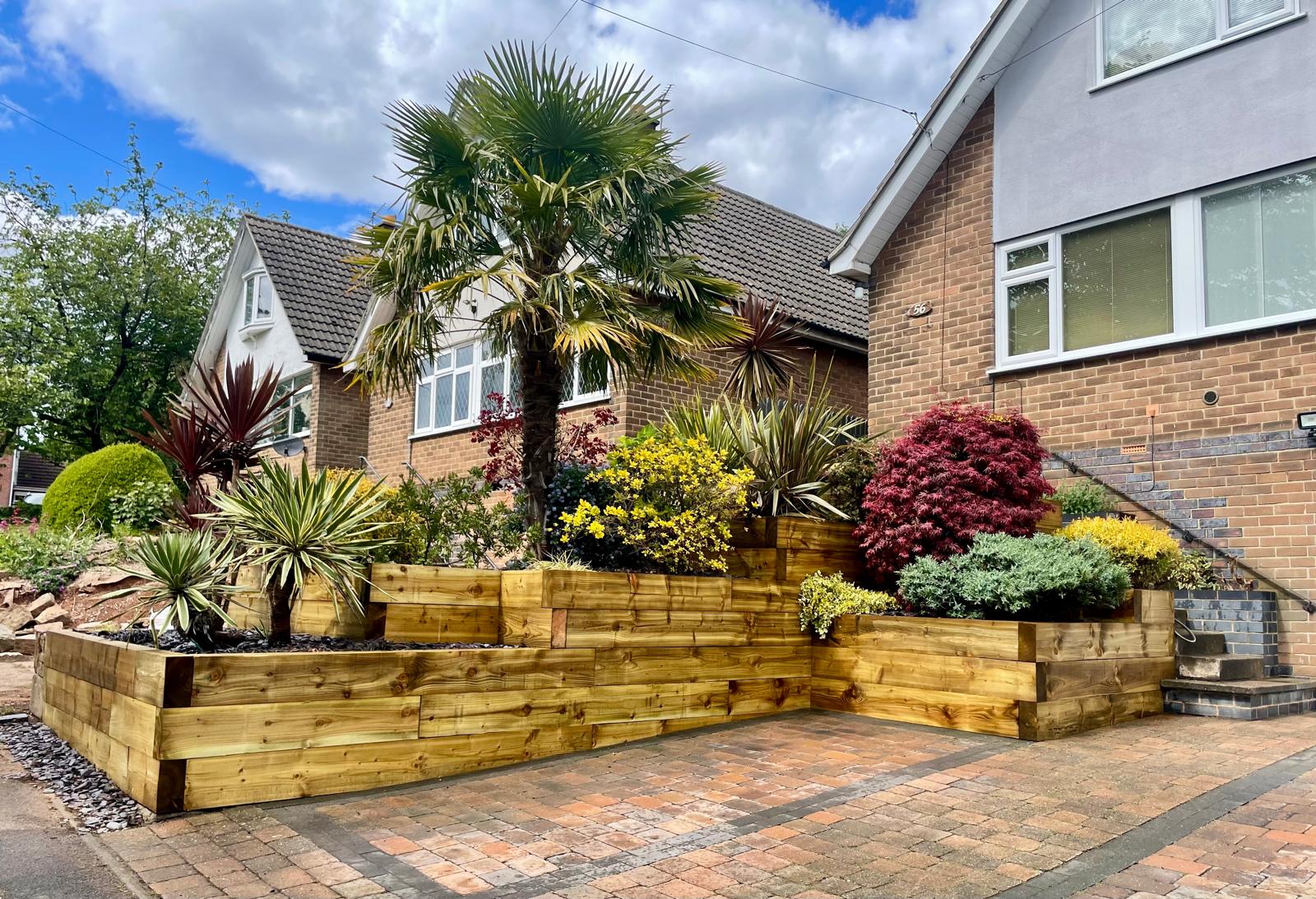 Front garden with timber sleeper raised beds, trachycarpus palm and cordylines